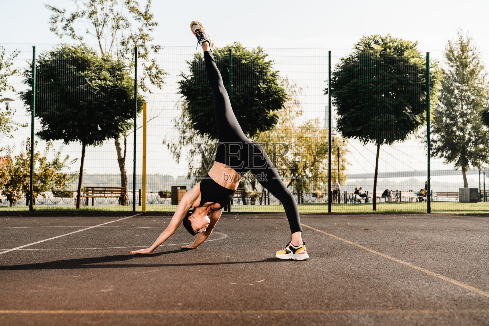 柔韧的年轻女运动员在运动场上伸展照片摄影图片