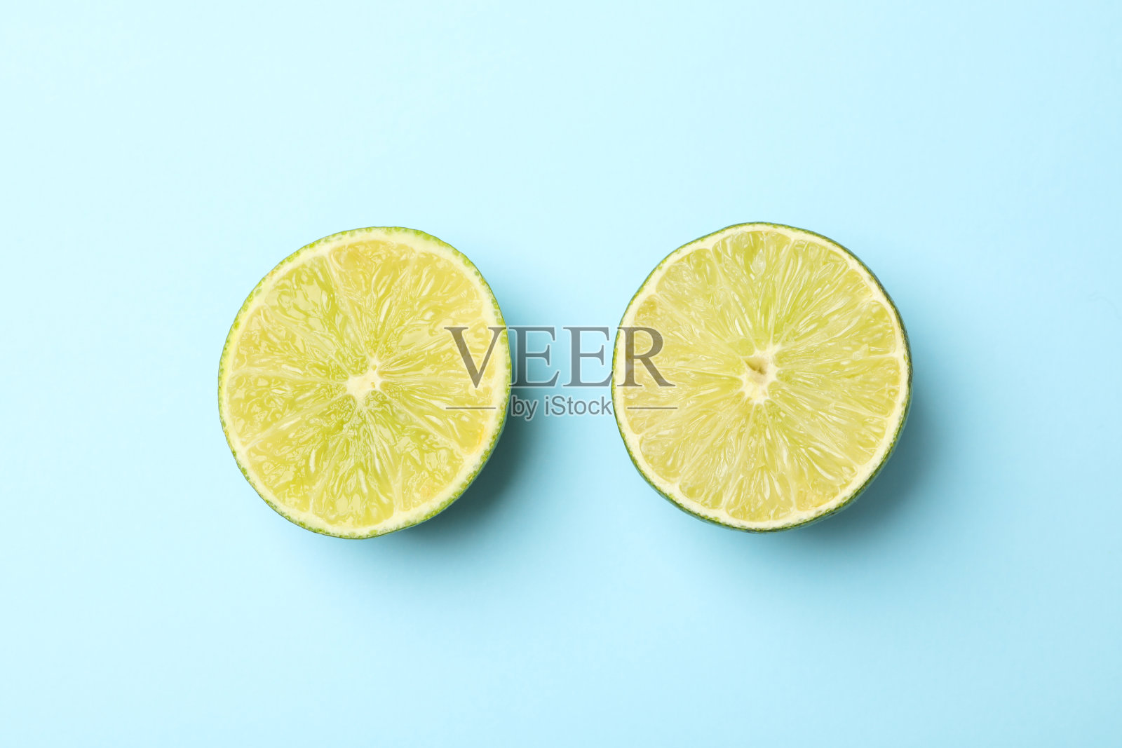 熟透的酸橙一半放在蓝色背景上，俯视图照片摄影图片