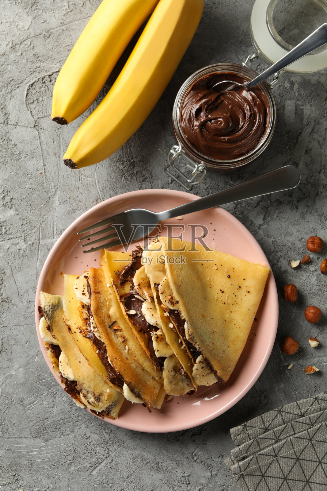 美味早餐的概念与可丽饼与巧克力酱，香蕉和坚果在灰色的背景照片摄影图片