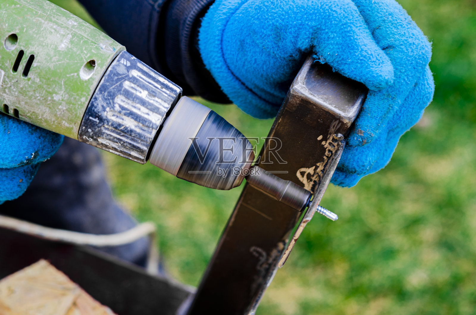 使金属制品。处理一个电动工具。那人的双手戴着带钻的手套照片摄影图片