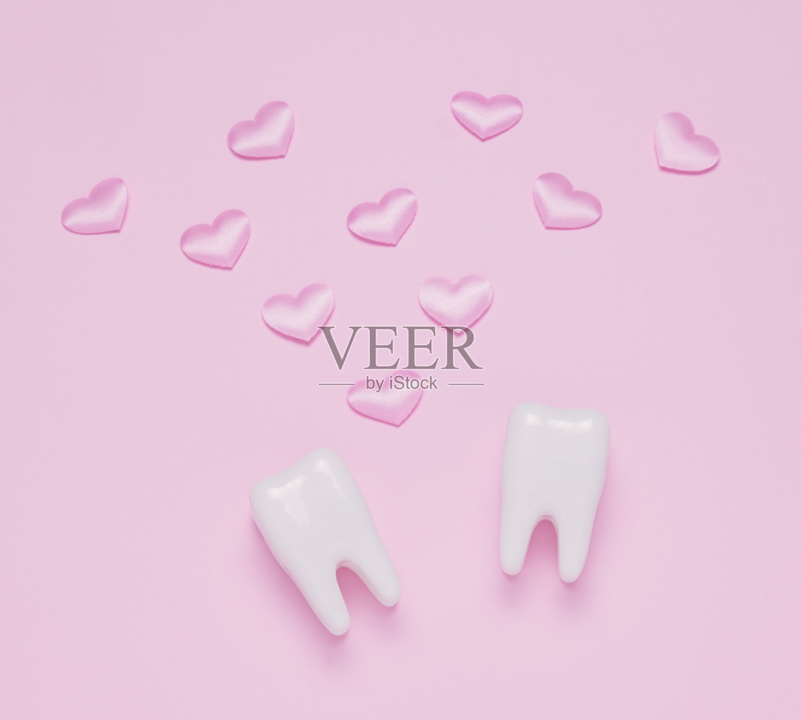俯视图平铺两颗牙齿粉红色心形粉色柔和的背景。照片摄影图片