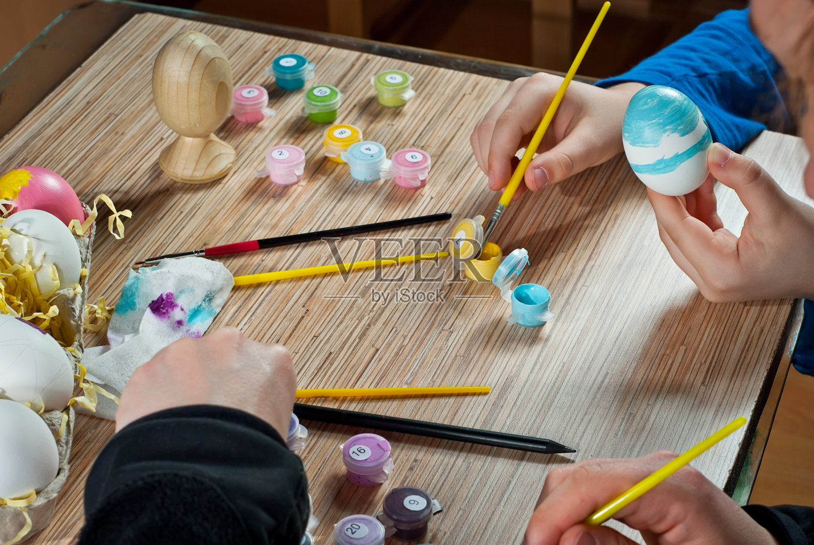 母子彩绘复活节彩蛋，木桌背景上摆放着彩色复活节彩蛋，是节日前传统的家庭娱乐活动照片摄影图片