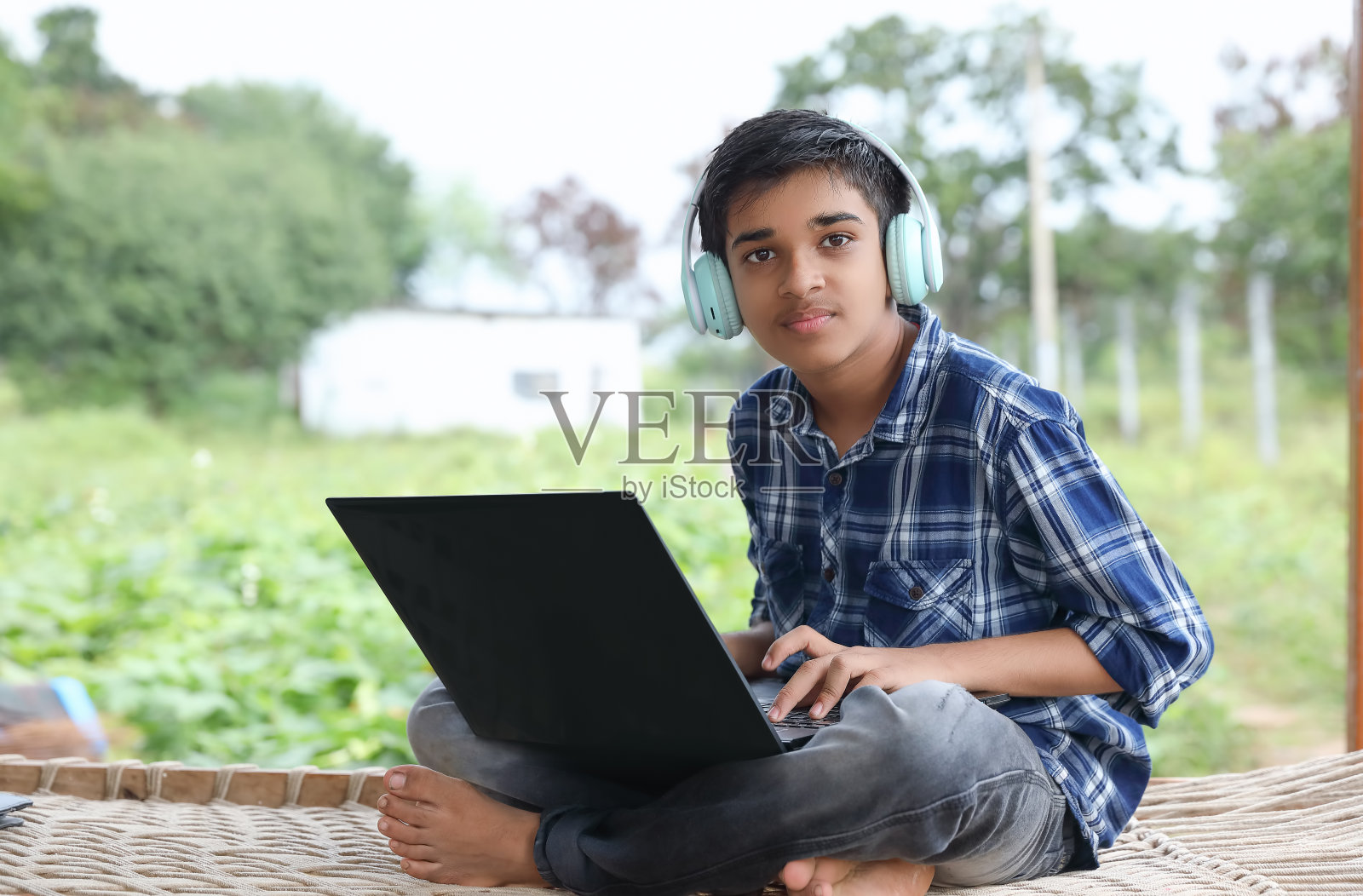 一个印度男孩在外面的家里上网络课程时使用笔记本电脑照片摄影图片