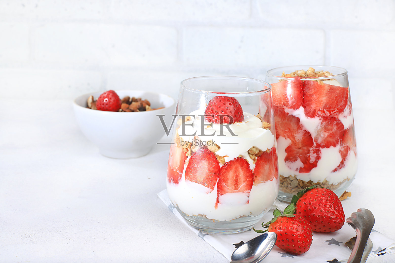 鲜亮的桌子上放着草莓酸奶、浆果和什锦麦片，还有水果沙拉。有用的早餐和配料。健康天然的食品理念、生活方式、儿童食品、选择性关注、照片摄影图片