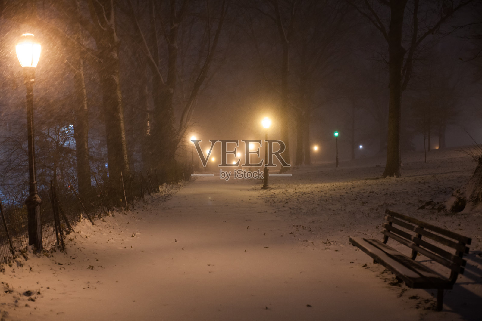 在一场暴风雪中，一条被雪覆盖的小路在黑暗中向远处退去照片摄影图片