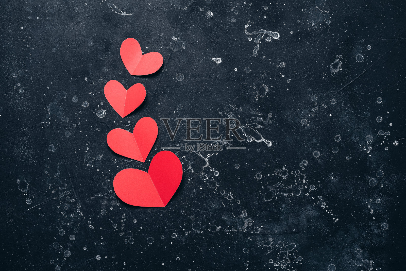 红纸心在黑石垃圾背景平lay。情人节。前视图。照片摄影图片