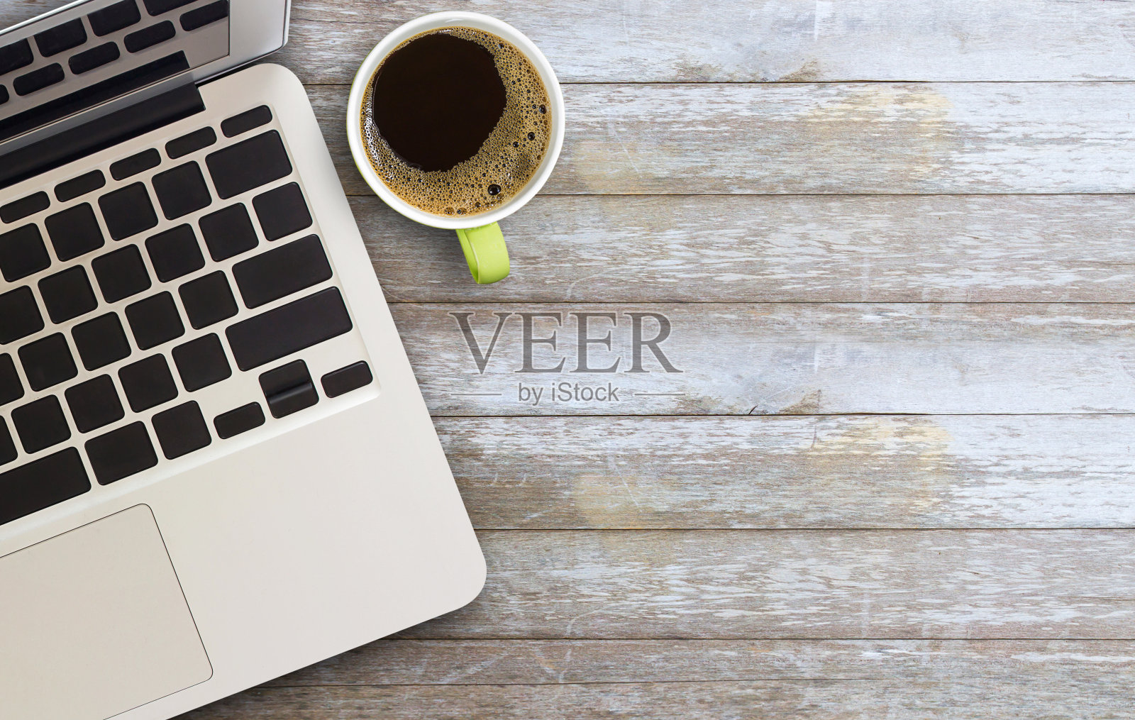 俯视图的笔记本电脑和一杯咖啡在棕色的木头桌子的背景。照片摄影图片