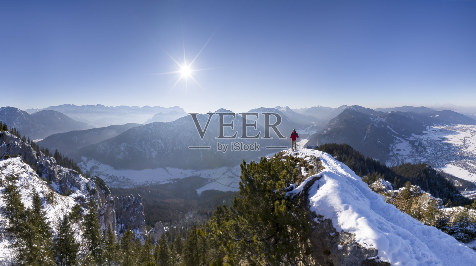在白雪覆盖的山顶上穿着红色夹克的徒步旅行者照片摄影图片