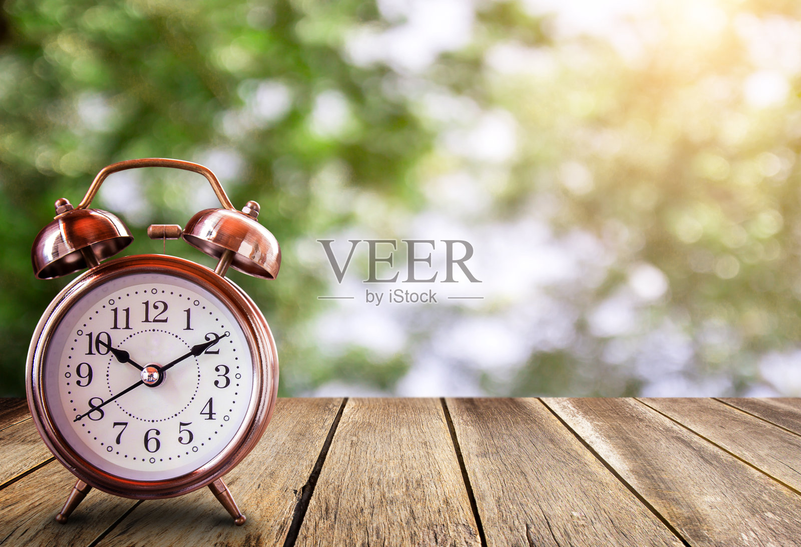 背景模糊的木桌上的复古闹钟。照片摄影图片
