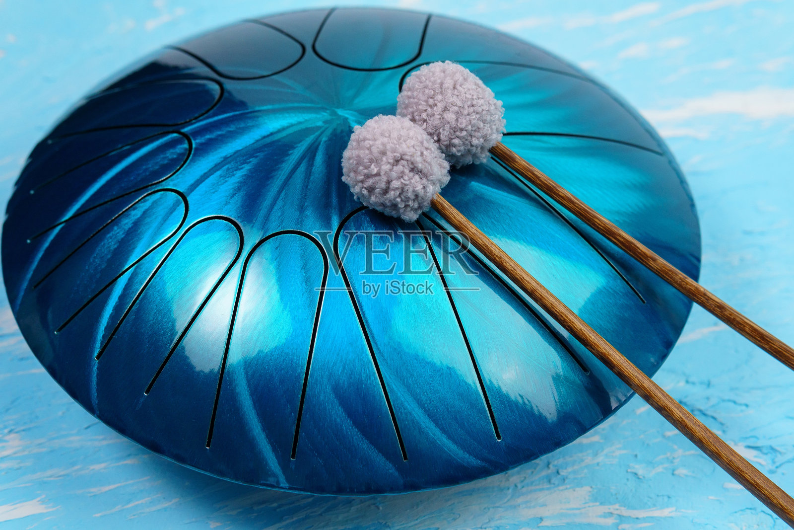 悬挂金属舌鼓，蓝色背景照片摄影图片