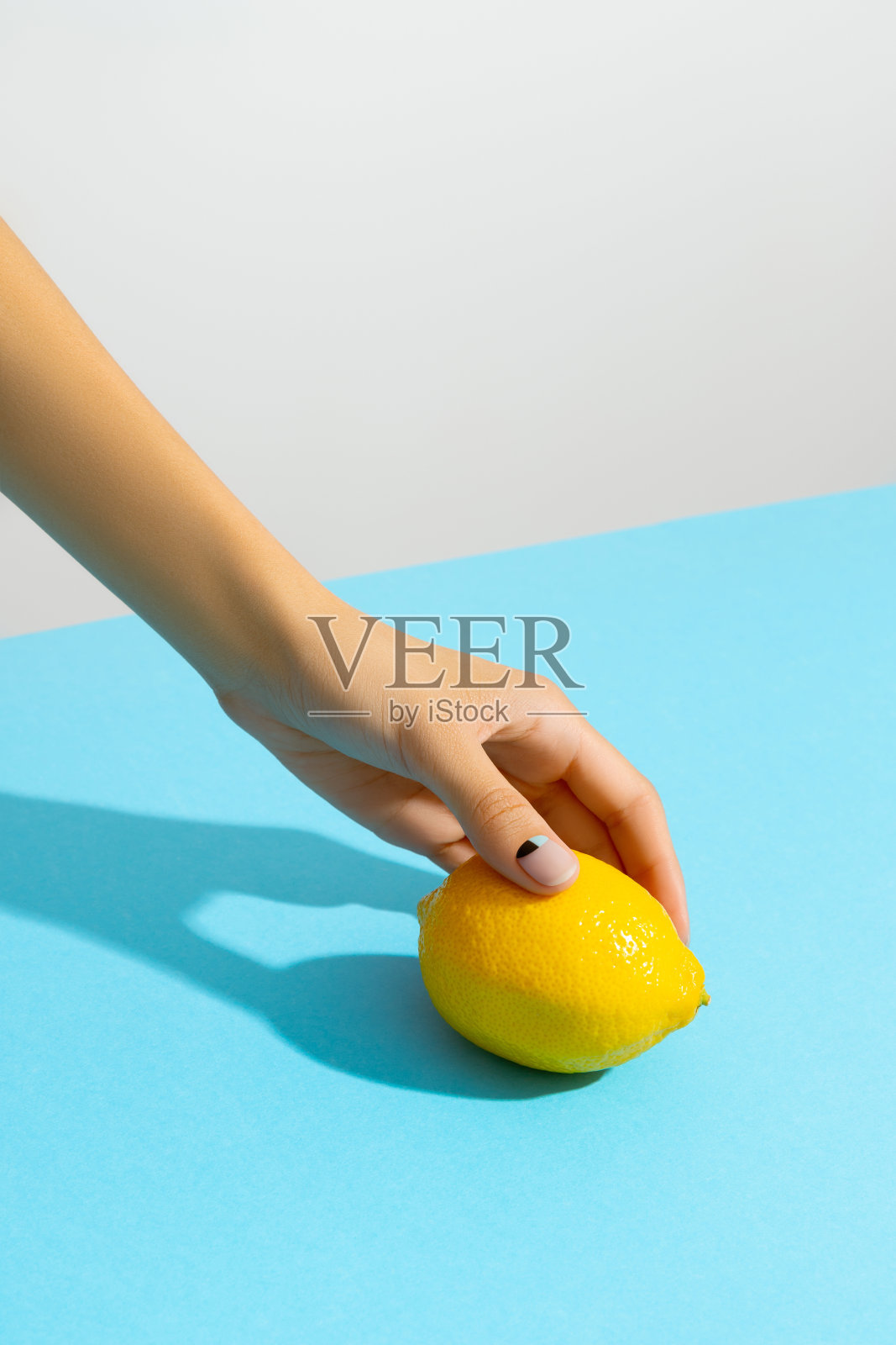 女人的手拿着柠檬在蓝色的背景照片摄影图片