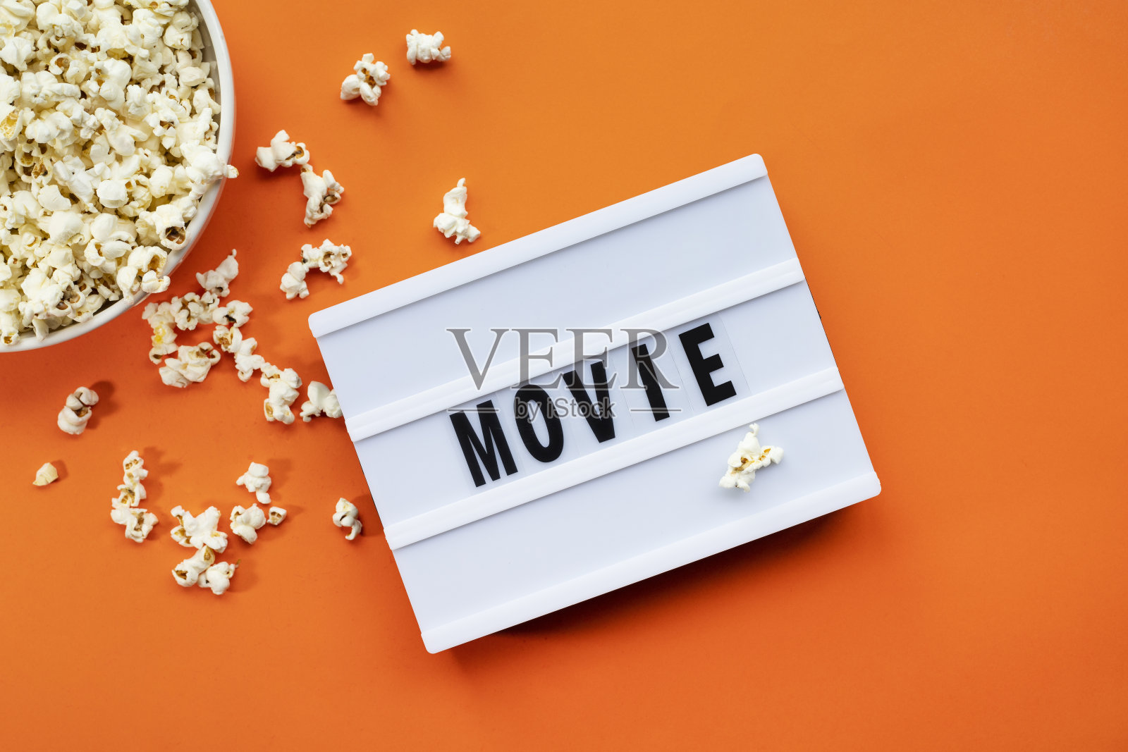 爆米花，灯箱文本电影时间在橙色的纸背景。前视图模板照片摄影图片