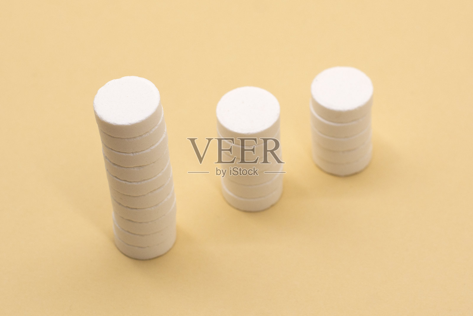 米色背景下的一堆药丸。由堆叠的白色药丸构成的增长图-增长的市场和对白色药丸及其替代品的需求。照片摄影图片