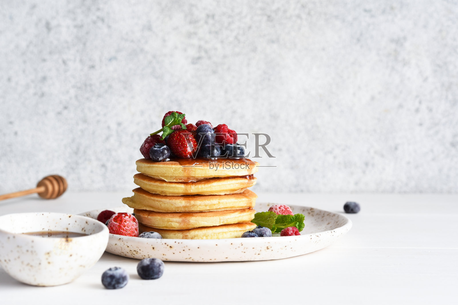 早餐是浆果煎饼和枫糖浆，背景是浅色的。照片摄影图片