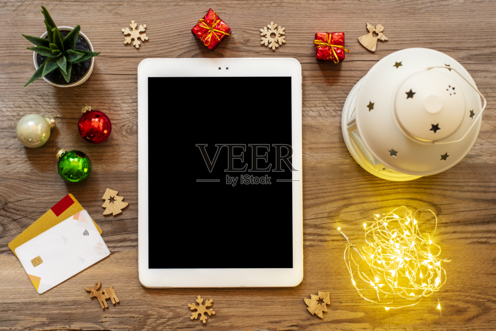 黑色屏幕的平板电脑，咖啡杯，借记卡，圣诞装饰，雪花在木桌上俯视图平铺假日购物清单，新年快乐，网上商店，选择礼物，使购买概念照片摄影图片