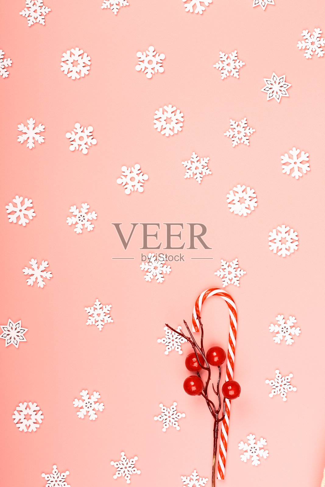 圣诞布局条纹棒棒糖与雪花和一枝红色浆果在粉红色的背景。放置文本，平面样式，顶视图。简约的北欧风格。照片摄影图片