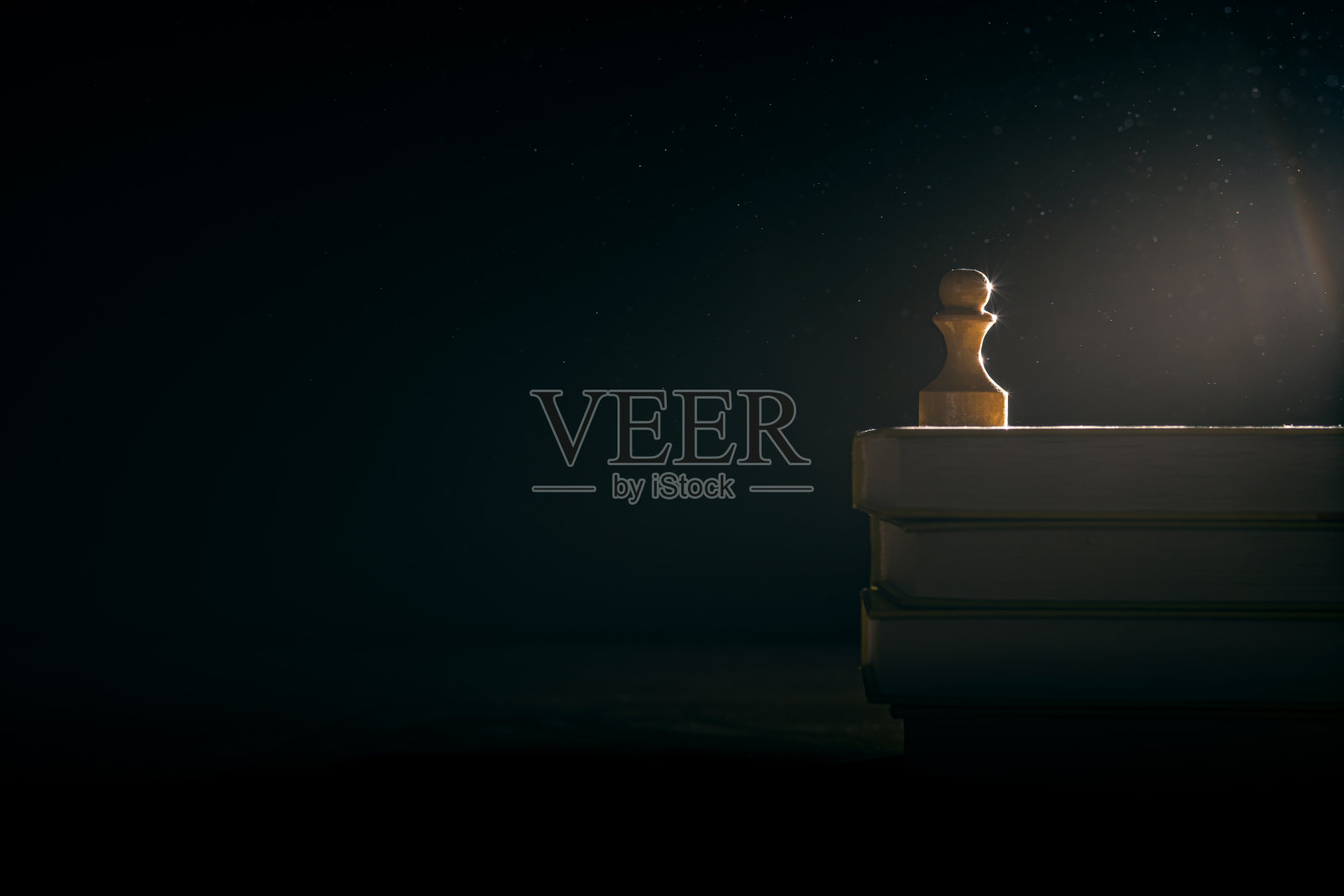 一个白色的木制棋子站在一堆古书上。模拟。文本空白照片摄影图片