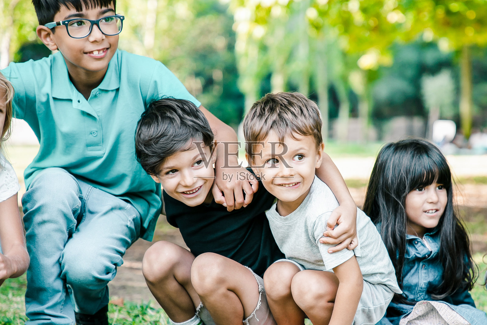 快乐的孩子们在草地上坐着蹲着照片摄影图片