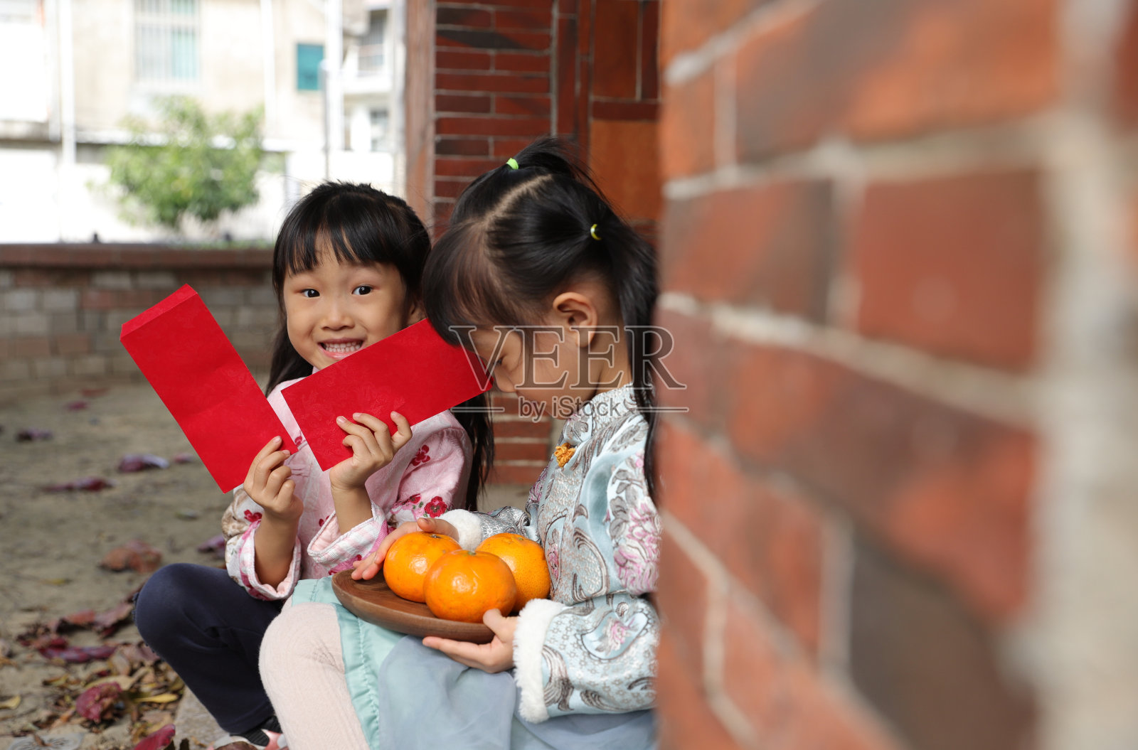 两个亚洲双胞胎女孩穿着旗袍在寺庙前进行新年访问。照片摄影图片