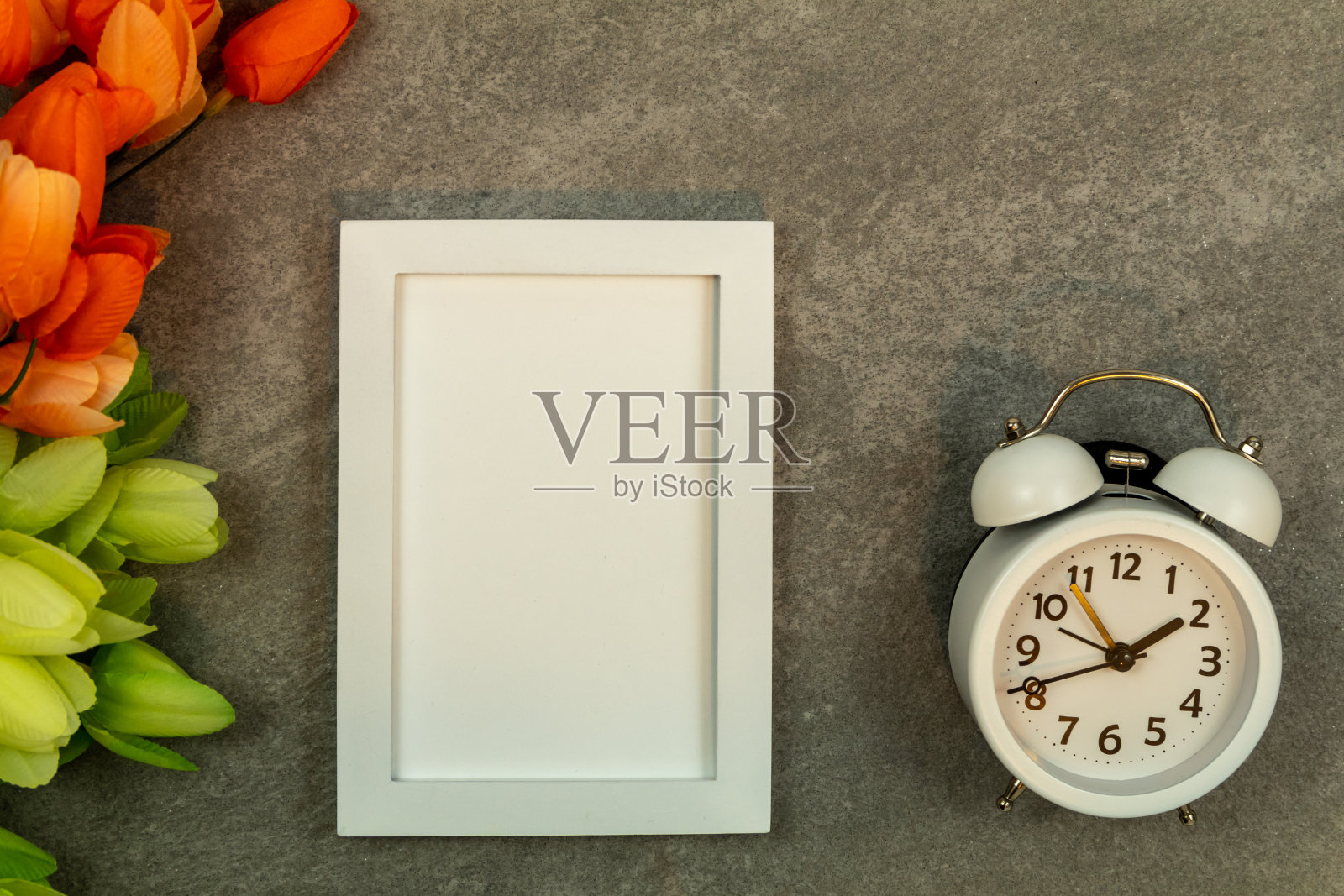 白色框架模型和闹钟在灰色花岗岩与郁金香平lay照片摄影图片