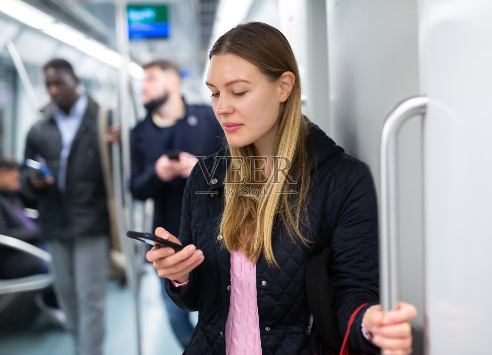 年轻女子在地铁里看手机照片摄影图片