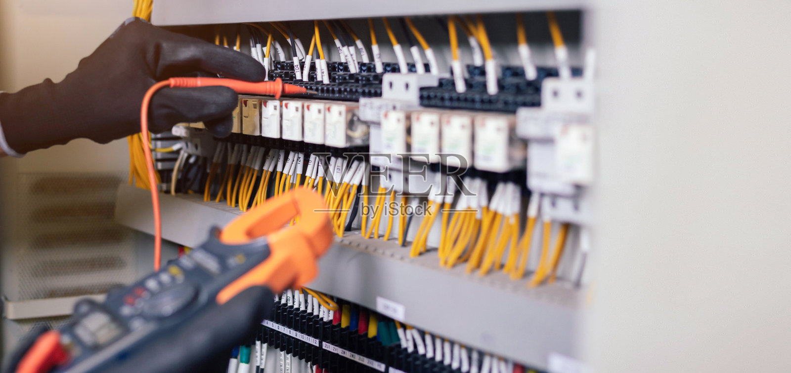 电工工程师在电控箱控制中进行电力线路电压和电流的测试。还有继电保护系统的电线。湾控制单元。中压开关设备。照片摄影图片