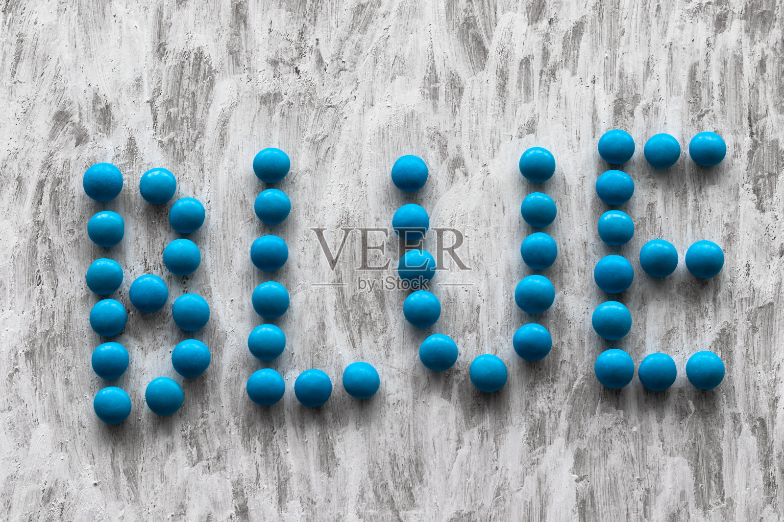 “蓝色”这个词是用丙烯酸颜料在白色的背景上用蓝色的糖果写的。一个来自食物的词。糖果。照片摄影图片