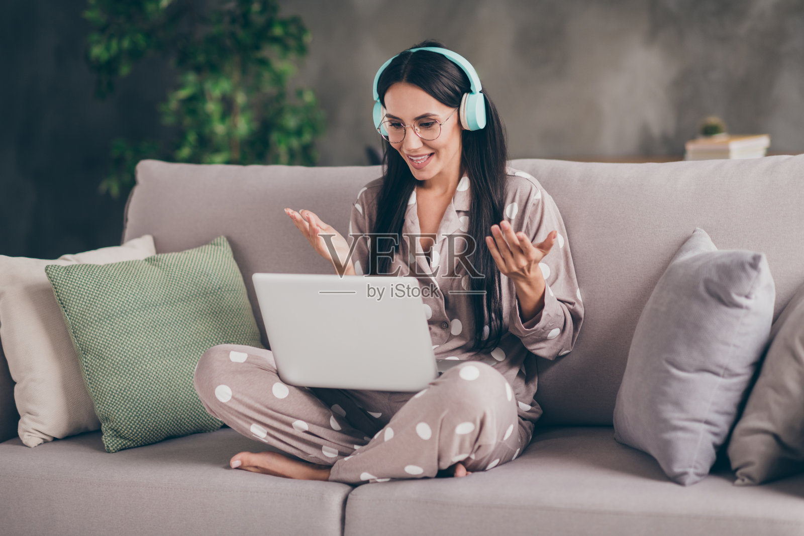 照片的好乐观的女孩坐在聊天笔记本电脑戴眼镜耳机睡衣在家里照片摄影图片
