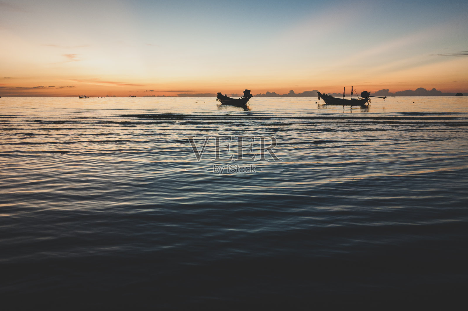 夕阳西下时，长尾船停泊在泰国高涛的海上照片摄影图片