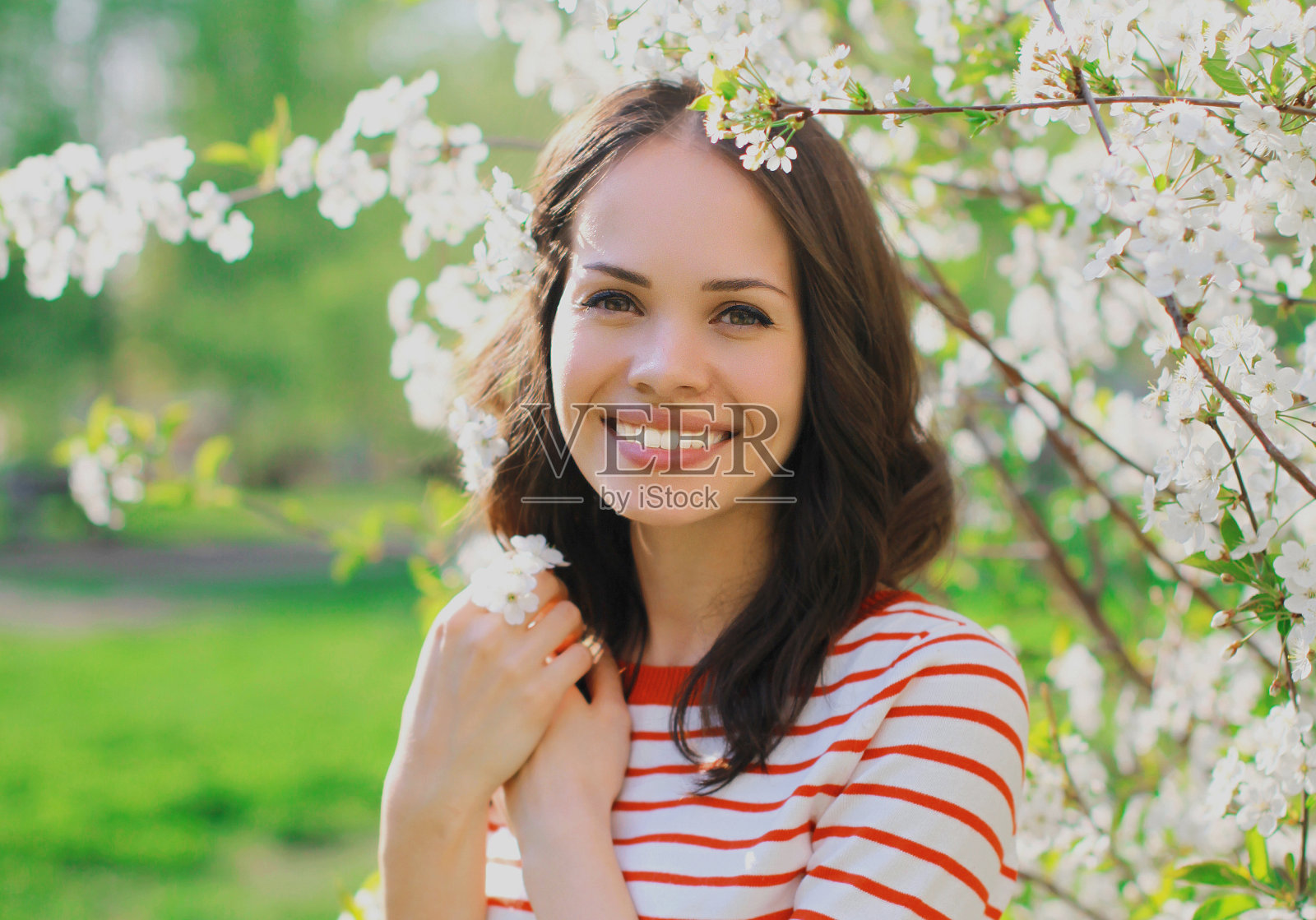肖像近距离的可爱的年轻女子在一个春天盛开的花园在一个白色的花的背景照片摄影图片