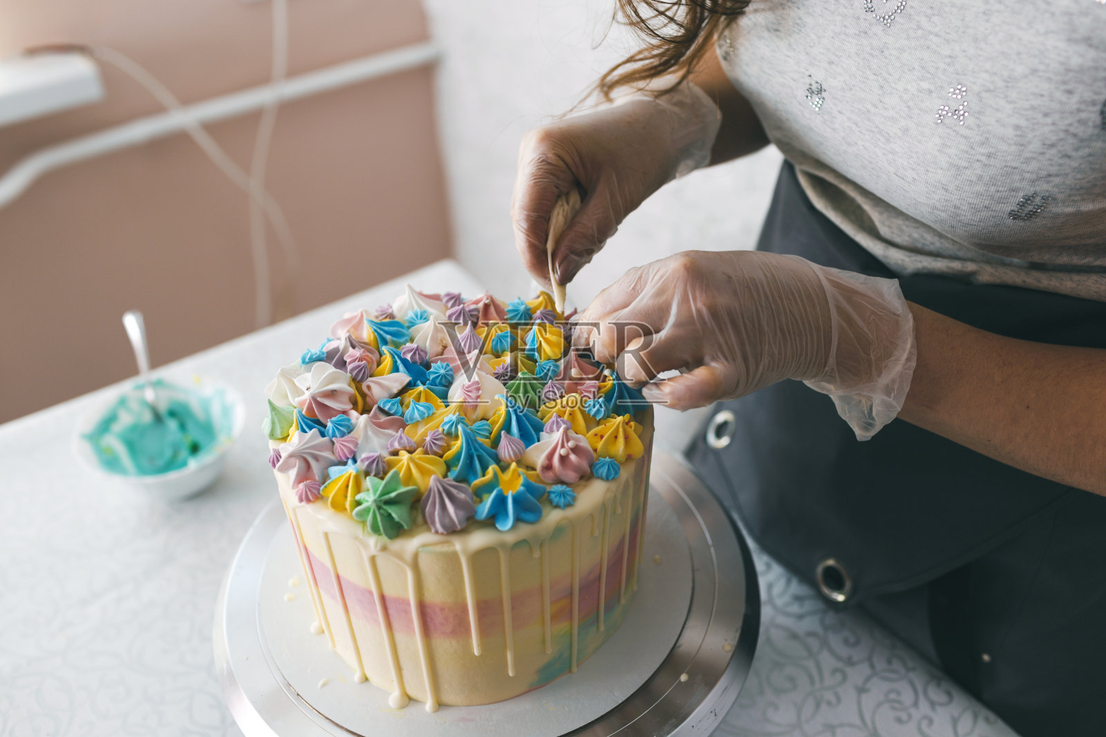 一位糕点师亲手制作了一个婚礼蛋糕，并在蛋糕上用奶油做了五颜六色的装饰。庆祝活动的准备照片摄影图片