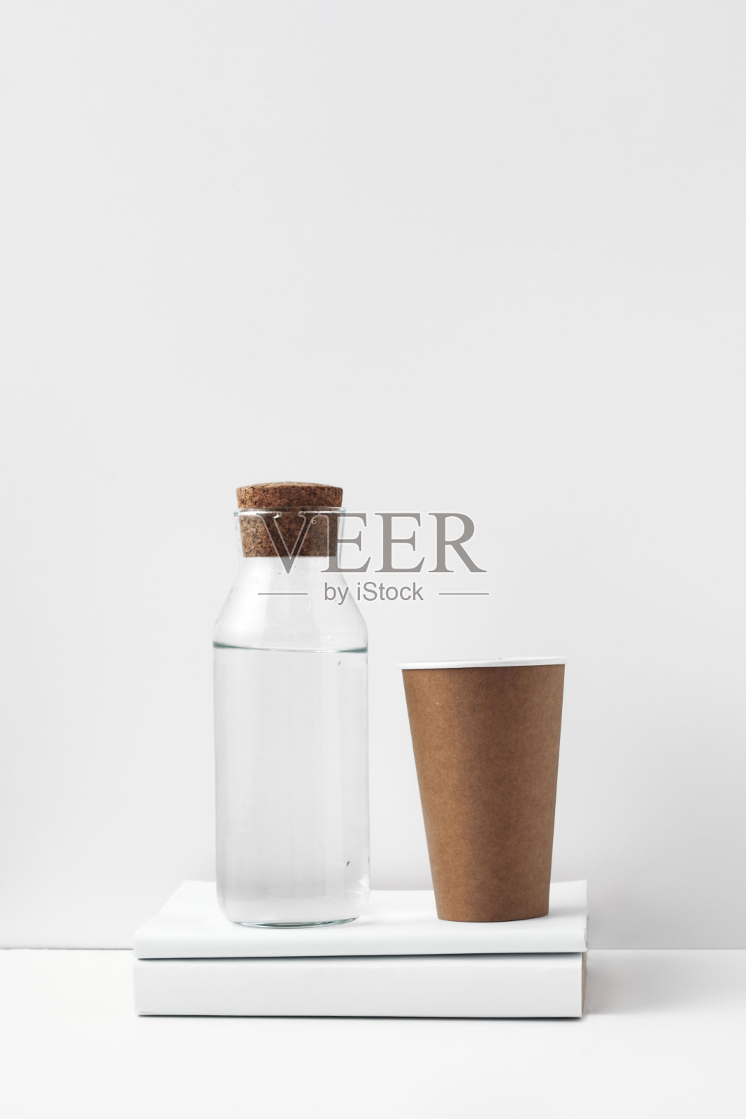 透明的瓶子与软木塞，纸杯和书在白色的背景。室内装饰采用天然环保材料。复制空间，模拟照片摄影图片