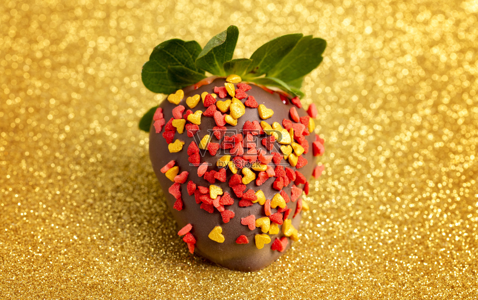 巧克力覆盖草莓覆盖在金色闪烁的点缀背景照片摄影图片