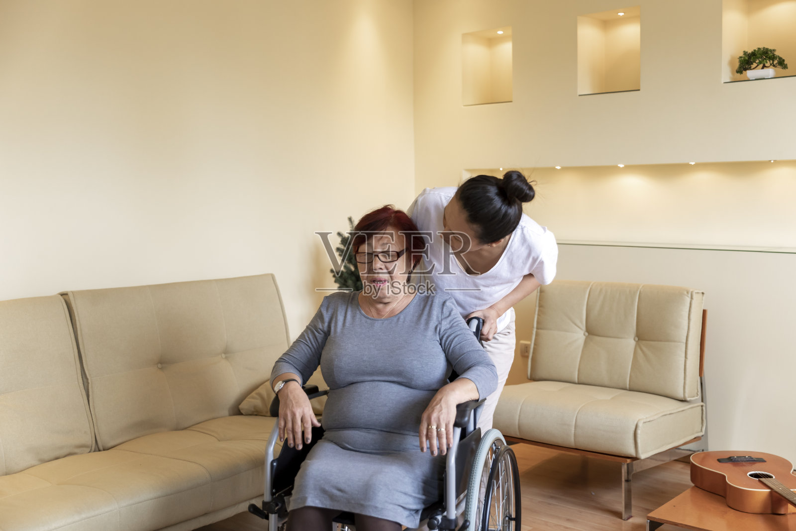 坐在轮椅上的老年妇女正在接受她女儿在家的帮助。照片摄影图片