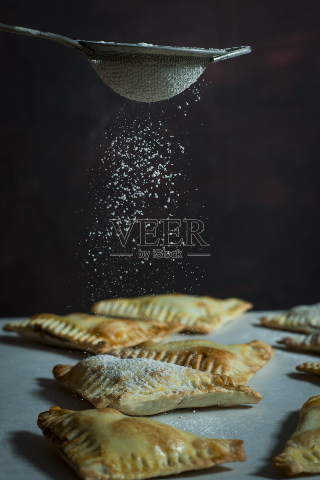 糖落在巧克力酱手派上。自制的甜点。照片摄影图片