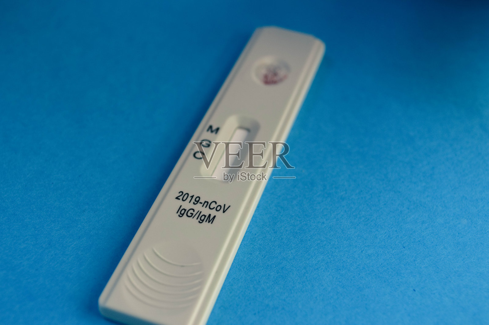 蓝色背景下冠状病毒检测试纸条。一滴血液上的敏感试验，以确定IgG和IgM抗体照片摄影图片