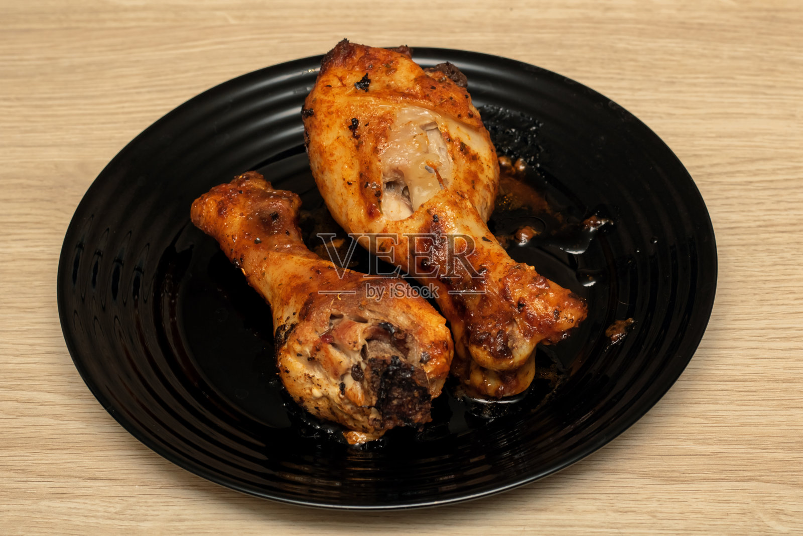 木桌上的盘子里放着烤鸡腿照片摄影图片