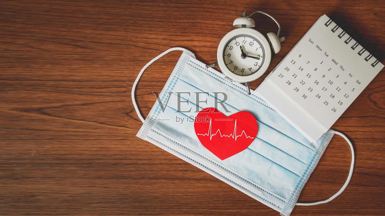 医用口罩、日历、时钟上有红色心形配白热跳动线，检查健康预约，谨防健康，因新冠肺炎放松封锁后的新常态生活方式照片摄影图片