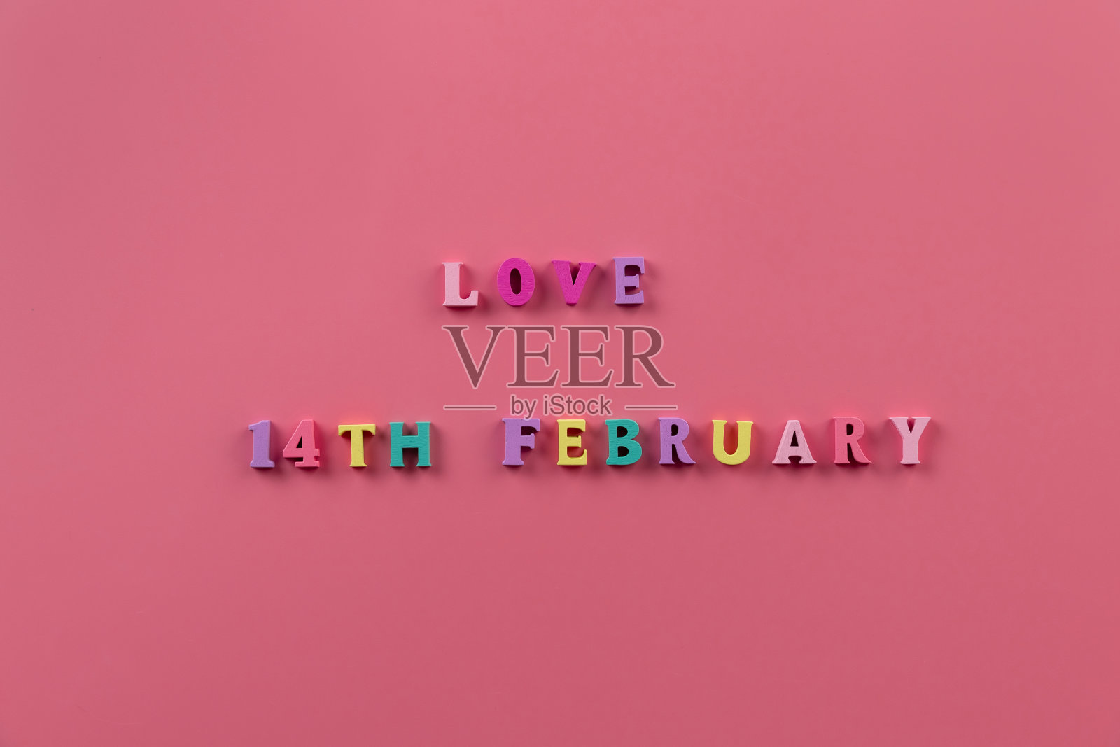 “2月14日爱”的横幅。粉红色背景上的多色字母。情人节的爱情主题。爱,积极的情感。节日快乐。庆祝和爱的概念。照片摄影图片