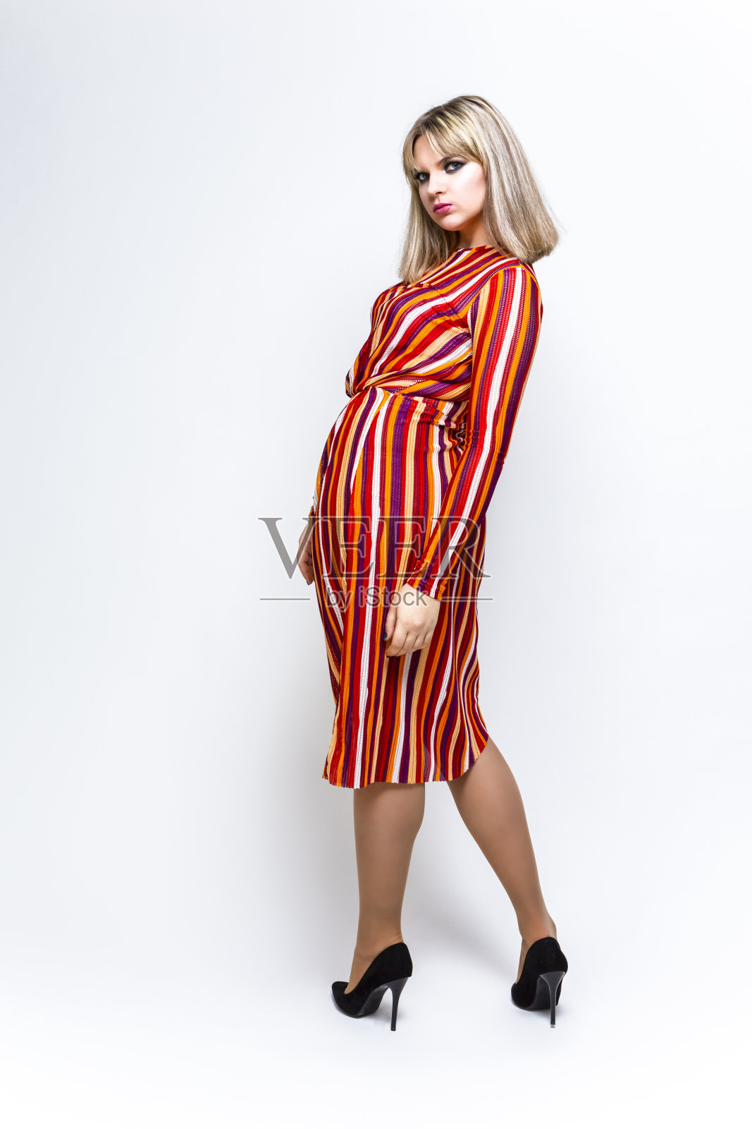 青春的概念。冷静的白种人金发女孩的完整长度肖像在鲜艳的条纹连衣裙反对白色。垂直的图像照片摄影图片