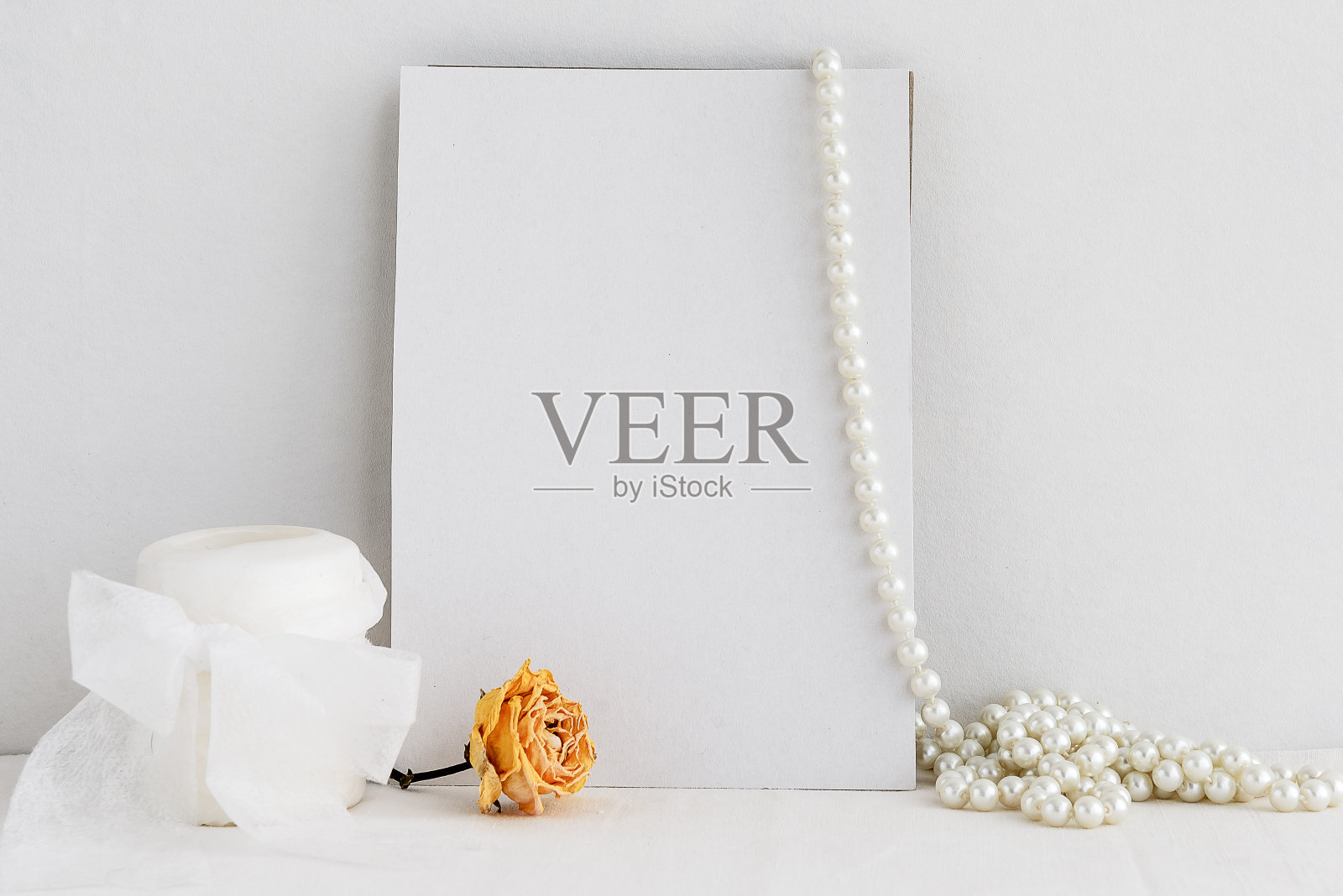 空白的白色贺卡，蜡烛和珍珠项链的白色背景。邀请的浪漫背景。照片摄影图片