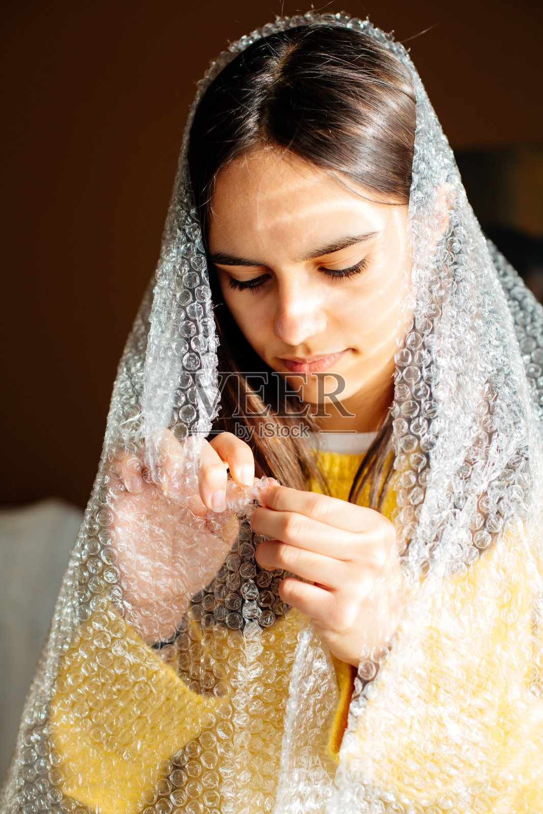 裹在气泡膜里戳气泡的少女照片摄影图片