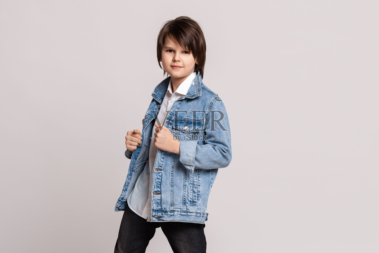 帅气时尚小男孩在牛仔夹克摆姿势和舞蹈在工作室。模型试验。时尚与人的概念照片摄影图片