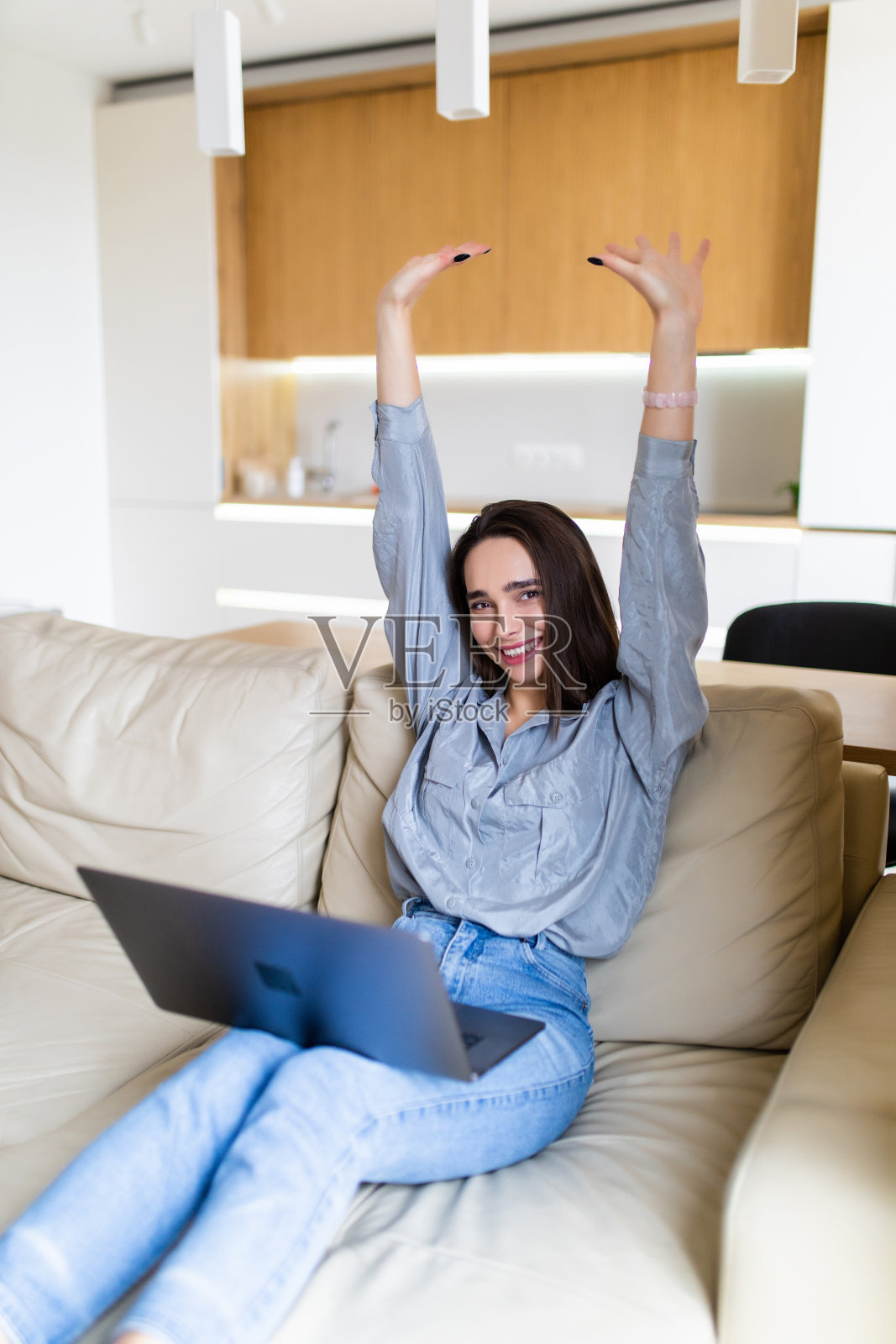 年轻女子坐在沙发上用笔记本电脑庆祝好消息照片摄影图片