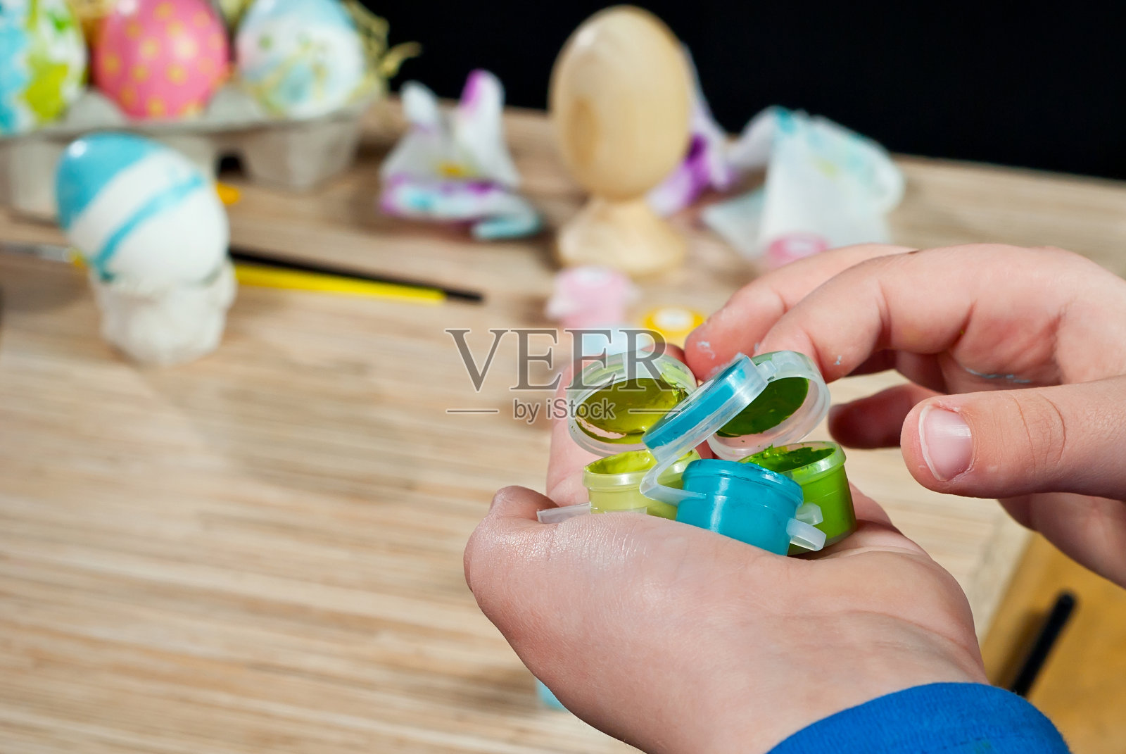 那个男孩画一个复活节彩蛋。手握颜料，特写。照片摄影图片