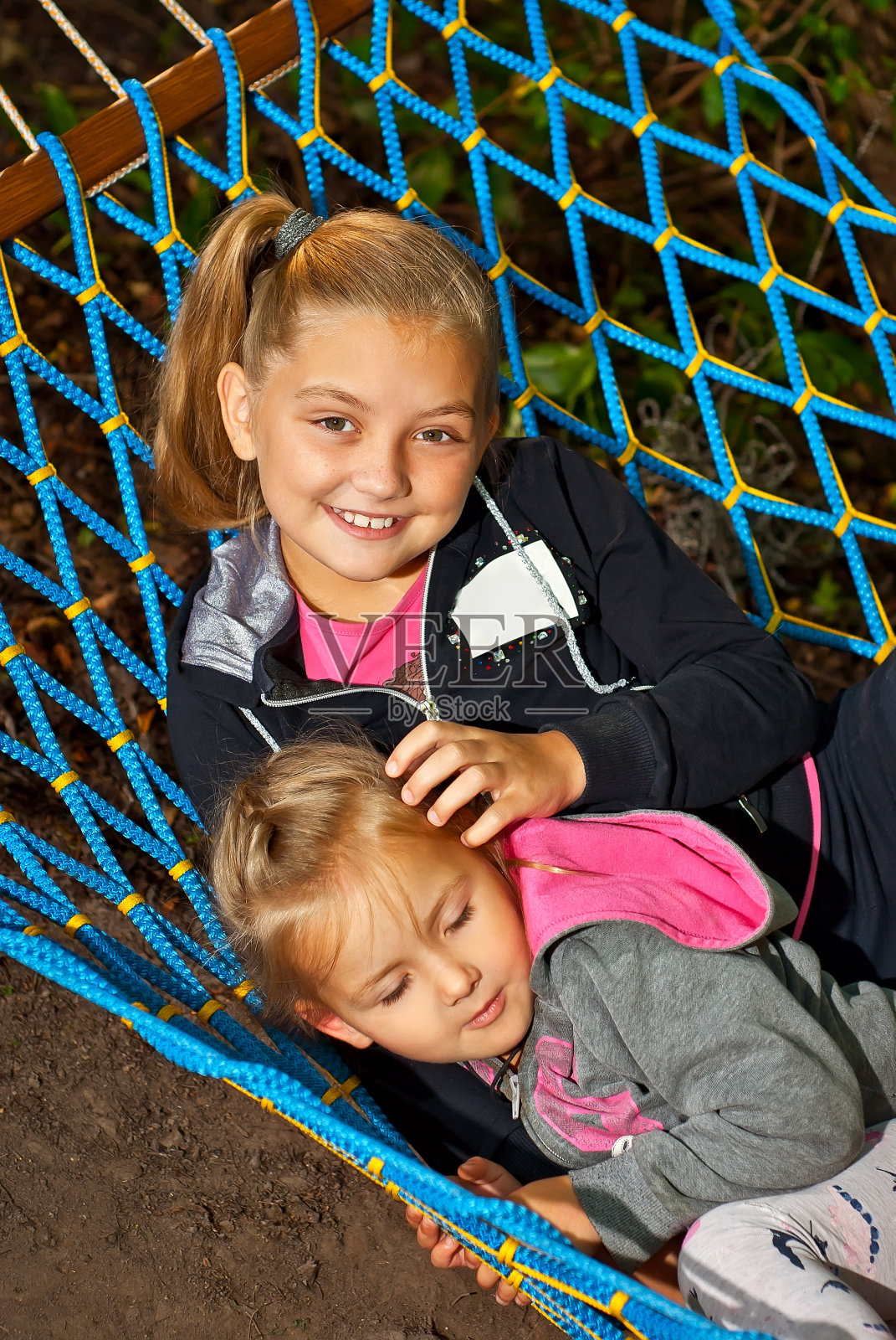 孩子们坐在吊床上。夏天女孩们在大自然中玩耍。孩子们在花园里的娱乐活动。照片摄影图片