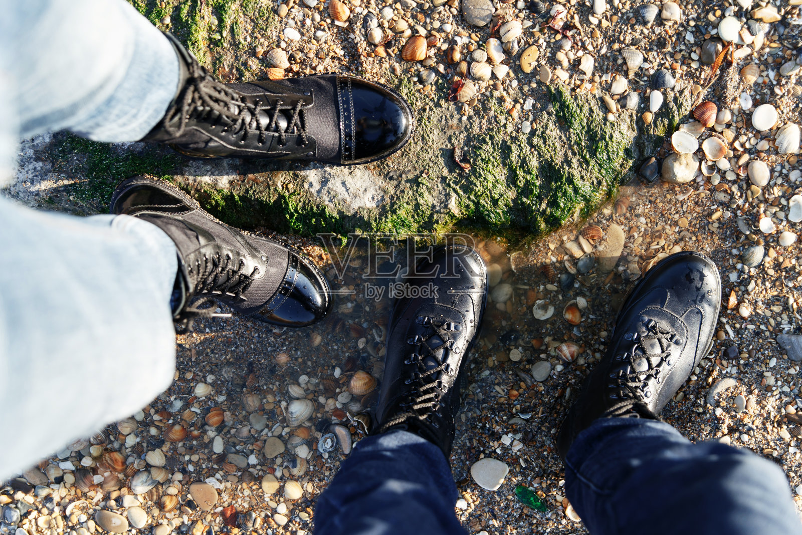 女孩和男孩穿着牛仔裤和黑色靴子在沙滩上步行，度过一个活跃的假期照片摄影图片