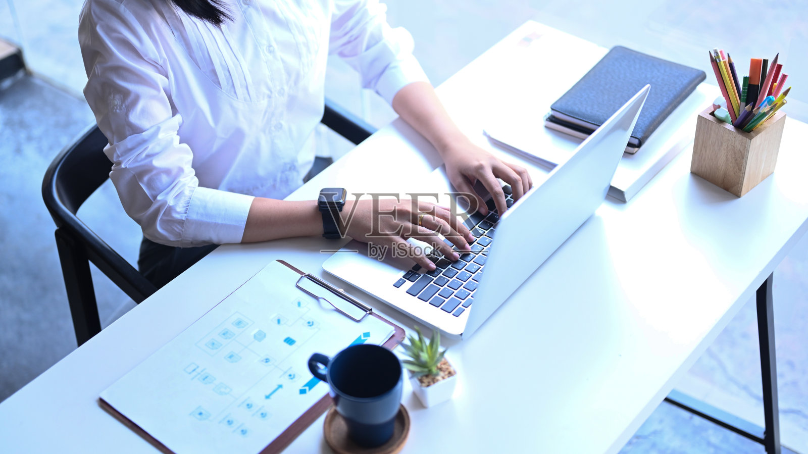 高空拍摄的女商人分析市场数据和工作在办公室的笔记本电脑。照片摄影图片