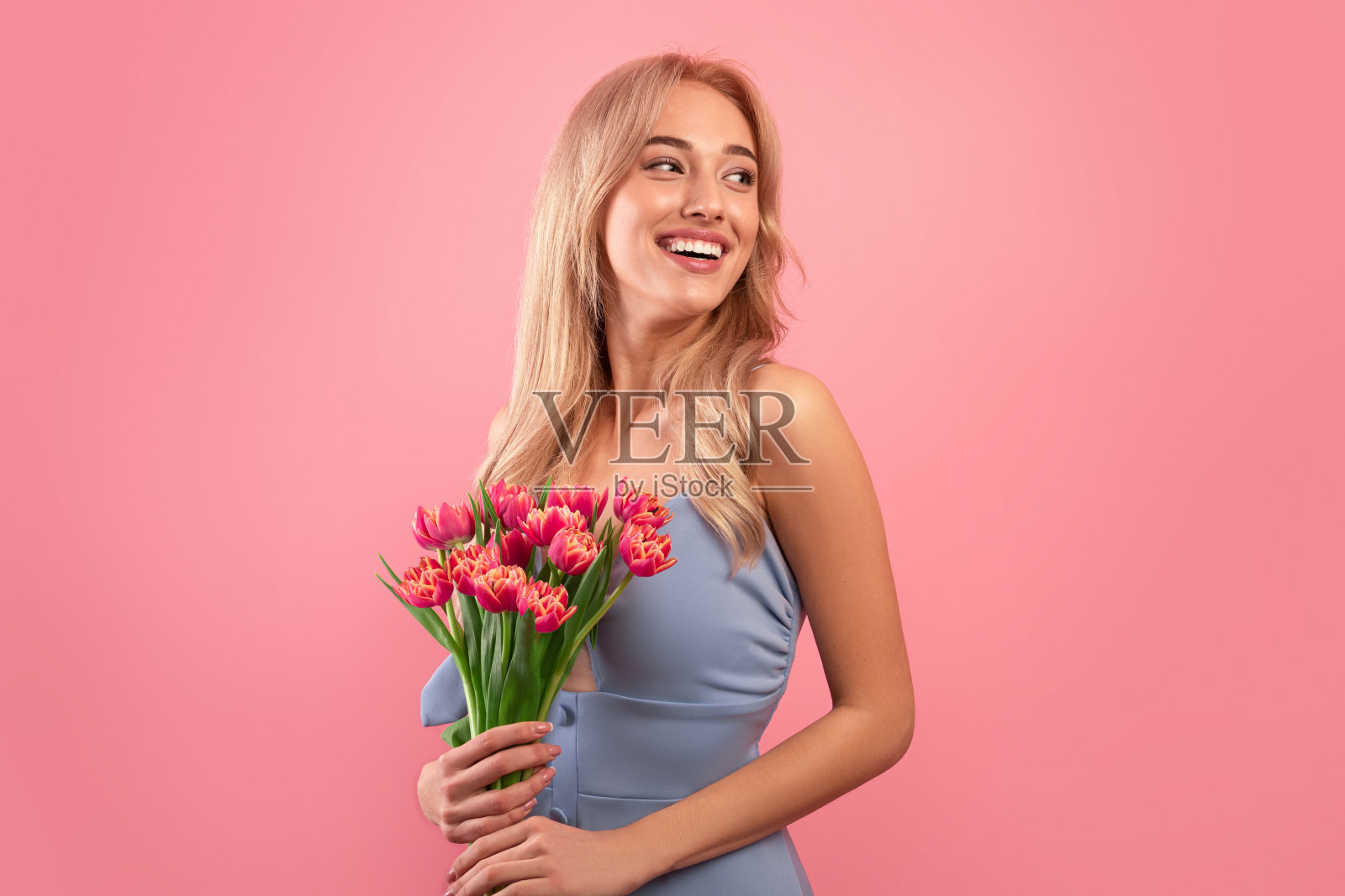 女人的一天。迷人的年轻女士与一束新鲜的郁金香庆祝春天假期在粉红色的工作室背景照片摄影图片