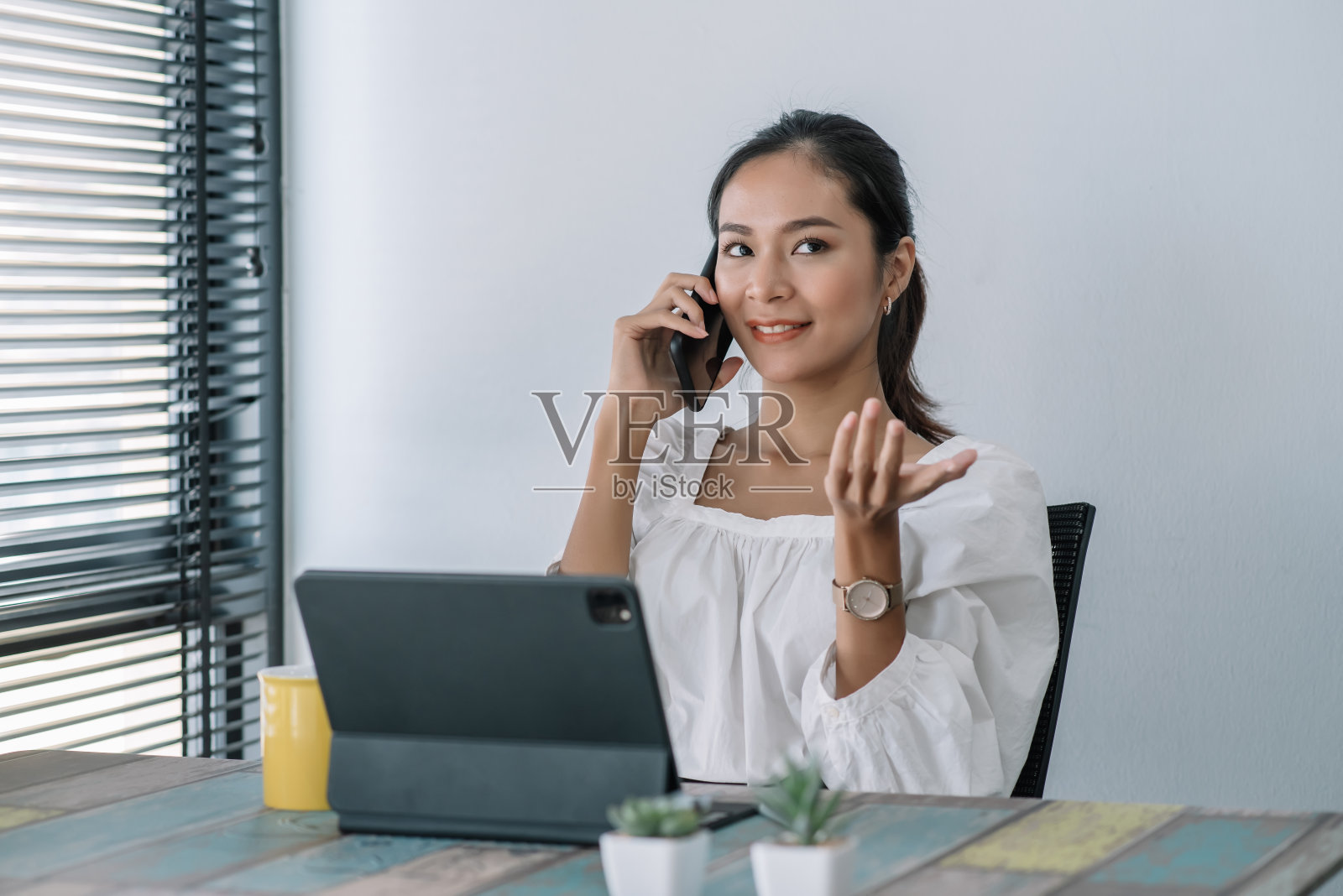 快乐年轻的亚洲商业女人美丽迷人的微笑和在办公室的移动电话交谈。照片摄影图片